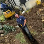 plumber digging to reach underground pipe